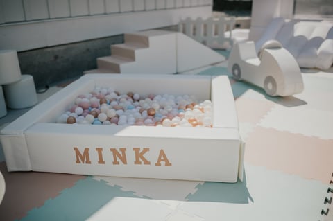 White MINKA ball pit filled with colorful plastic balls in a playroom setting with white and blue flooring